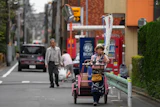 Akiko Sugaya blows a horn while she peddles tofu, prepared food and beverages in a cart in Tokyo, July 4, 2026.