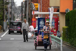 Akiko Sugaya blows a horn while she peddles tofu, prepared food and beverages in a cart in Tokyo, July 4, 2026.