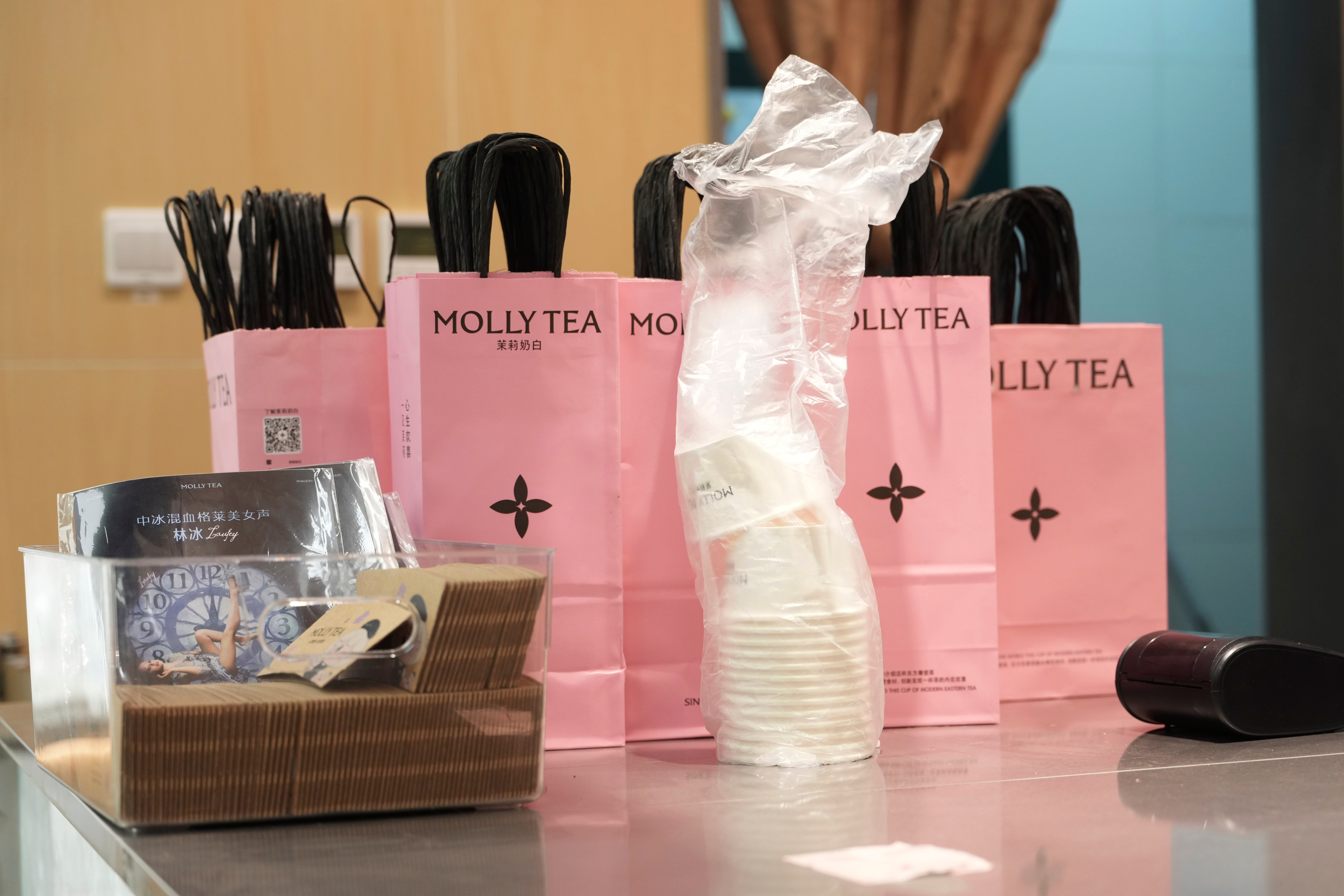 Bags with the Molly Tea brand and logo at a shop in Beijing, July 7, 2026.