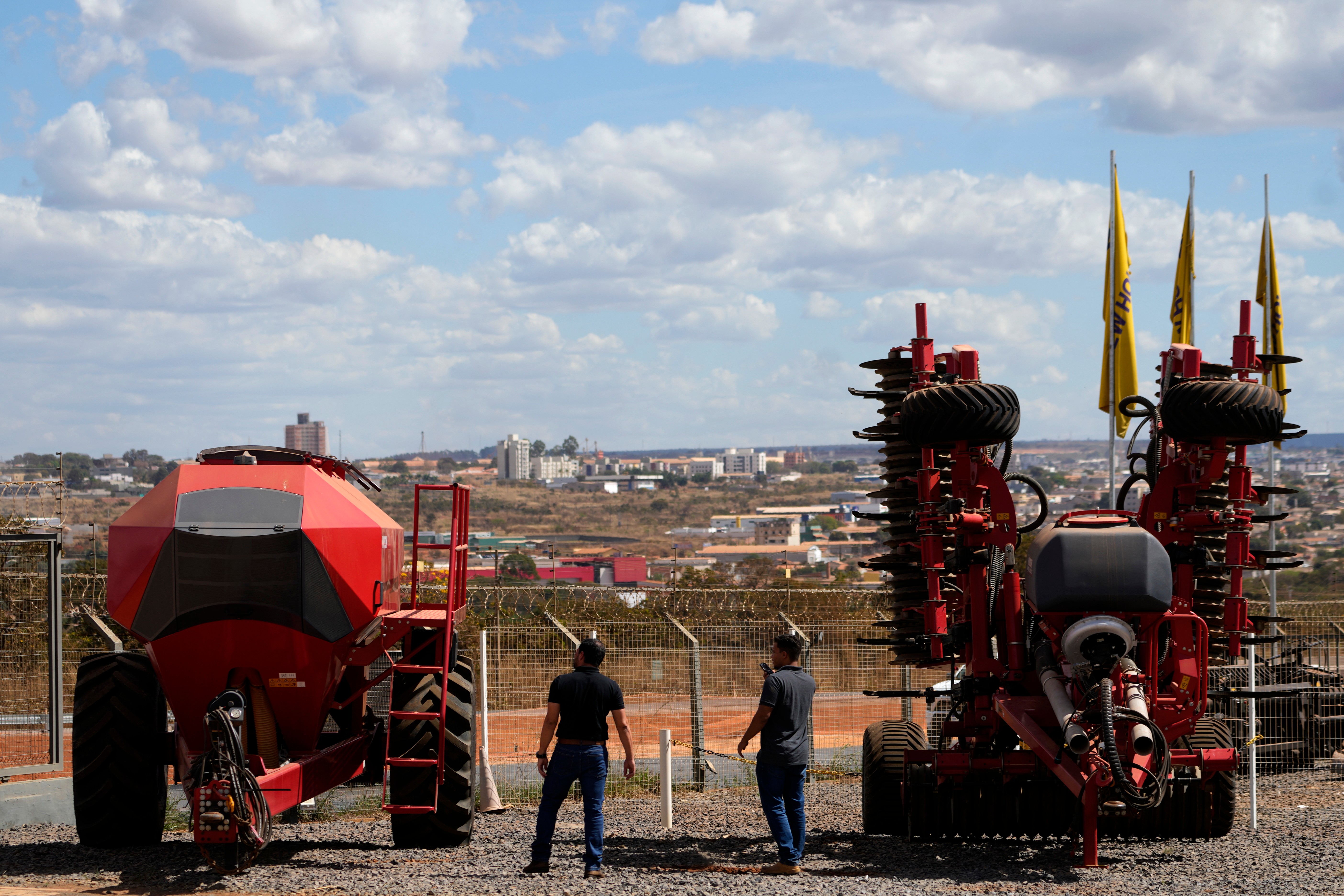 Salesmen walk among agricultural machinery displayed at an equipment dealership, Brasilia, Brazil, July 22, 2026.