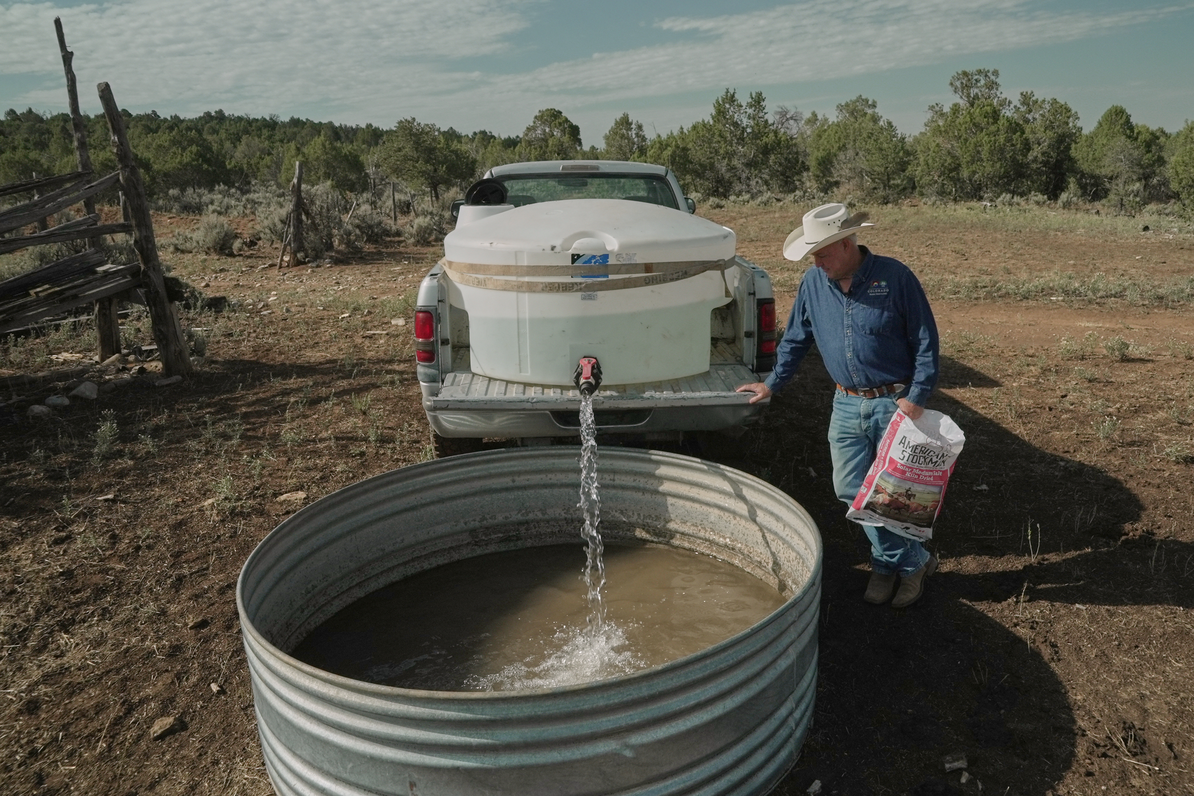 Mark Ragsdale refills a stock tank, July 17, 2026, Redvale, Colo.