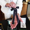 Auctioneer Jonathan Klunk shows a black bow tie worn by KFC founder Harland Sanders, Shelbyville, Ky., July 22, 2026.