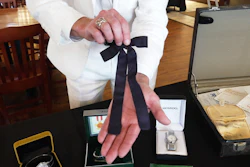 Auctioneer Jonathan Klunk shows a black bow tie worn by KFC founder Harland Sanders, Shelbyville, Ky., July 22, 2026.