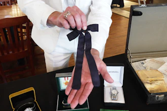 Auctioneer Jonathan Klunk shows a black bow tie worn by KFC founder Harland Sanders, Shelbyville, Ky., July 22, 2026.