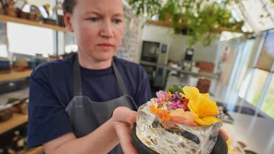 Noma's head of R&D Mette Brink Soberg holds a berry gazpacho dish topped with flower petals, Copenhagen, July 28, 2026.