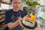 Noma's head of R&D Mette Brink Soberg holds a berry gazpacho dish topped with flower petals, Copenhagen, July 28, 2026.