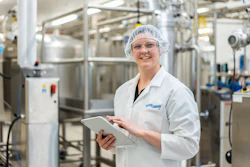 Lauren Zellner Standing In Front Of Equipment Smiling At Camera With Ipad