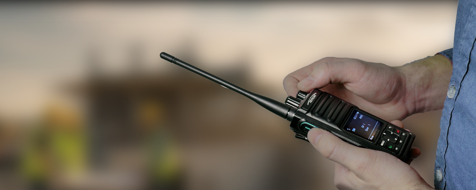 Person holding a black two-way radio with antenna outdoors