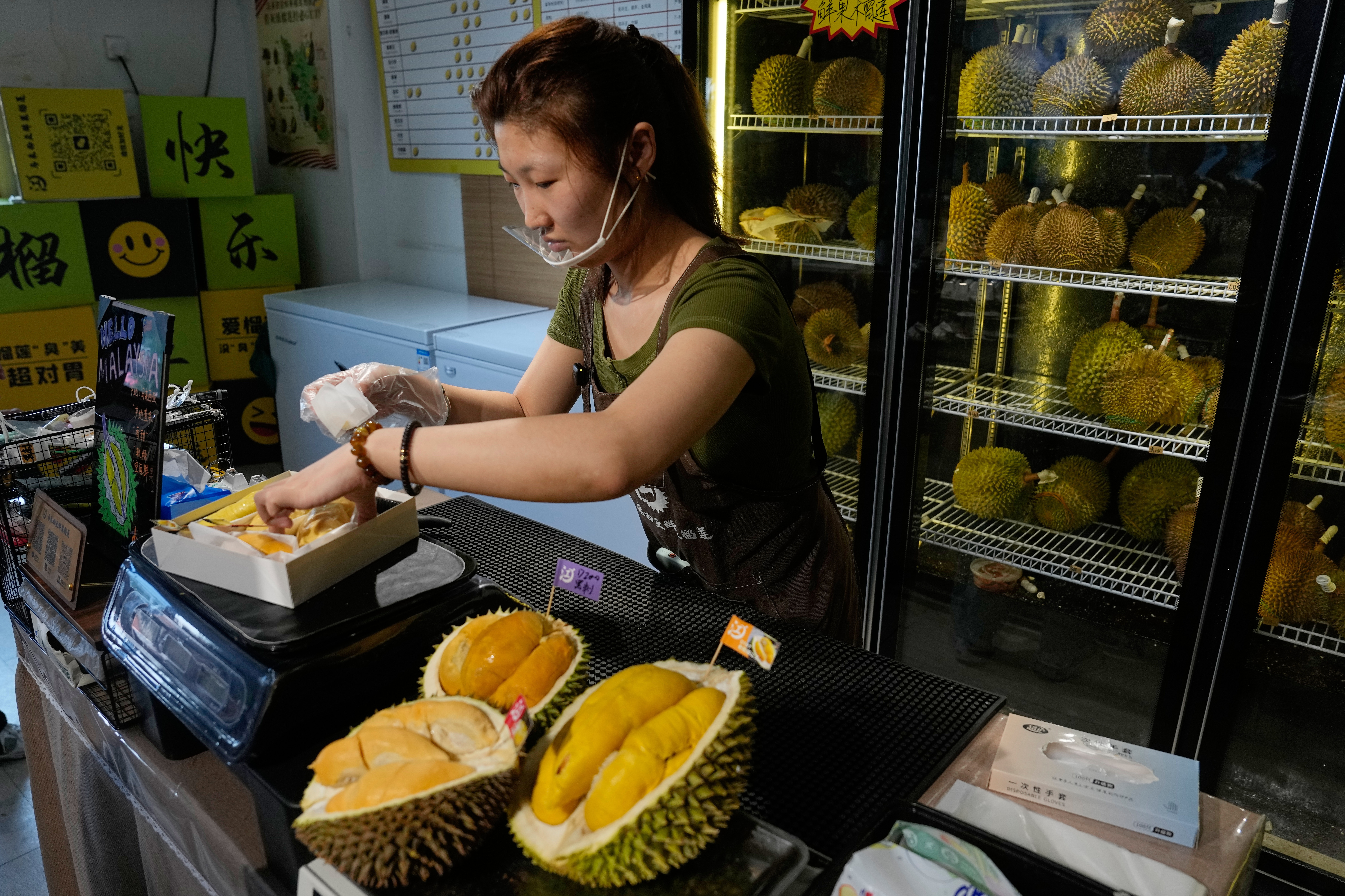 Worker Hou Yuxin packs durian fruit imported from Malaysia at a shop in Beijing, July 13, 2026.