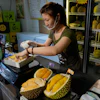 Worker Hou Yuxin packs durian fruit imported from Malaysia at a shop in Beijing, July 13, 2026.