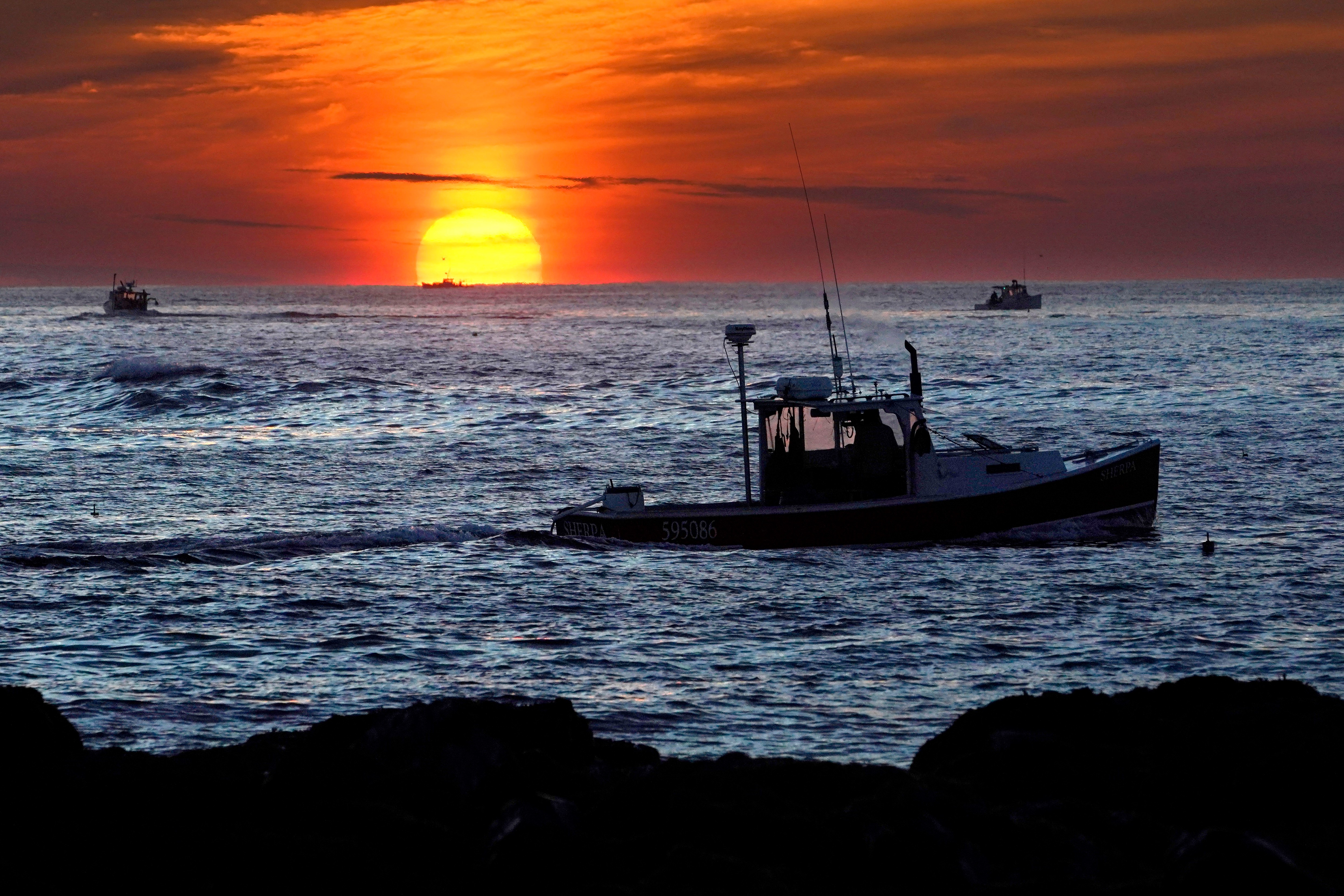 Lobster fishermen work at sunrise off Kennebunkport, Maine, Sept. 8, 2022.