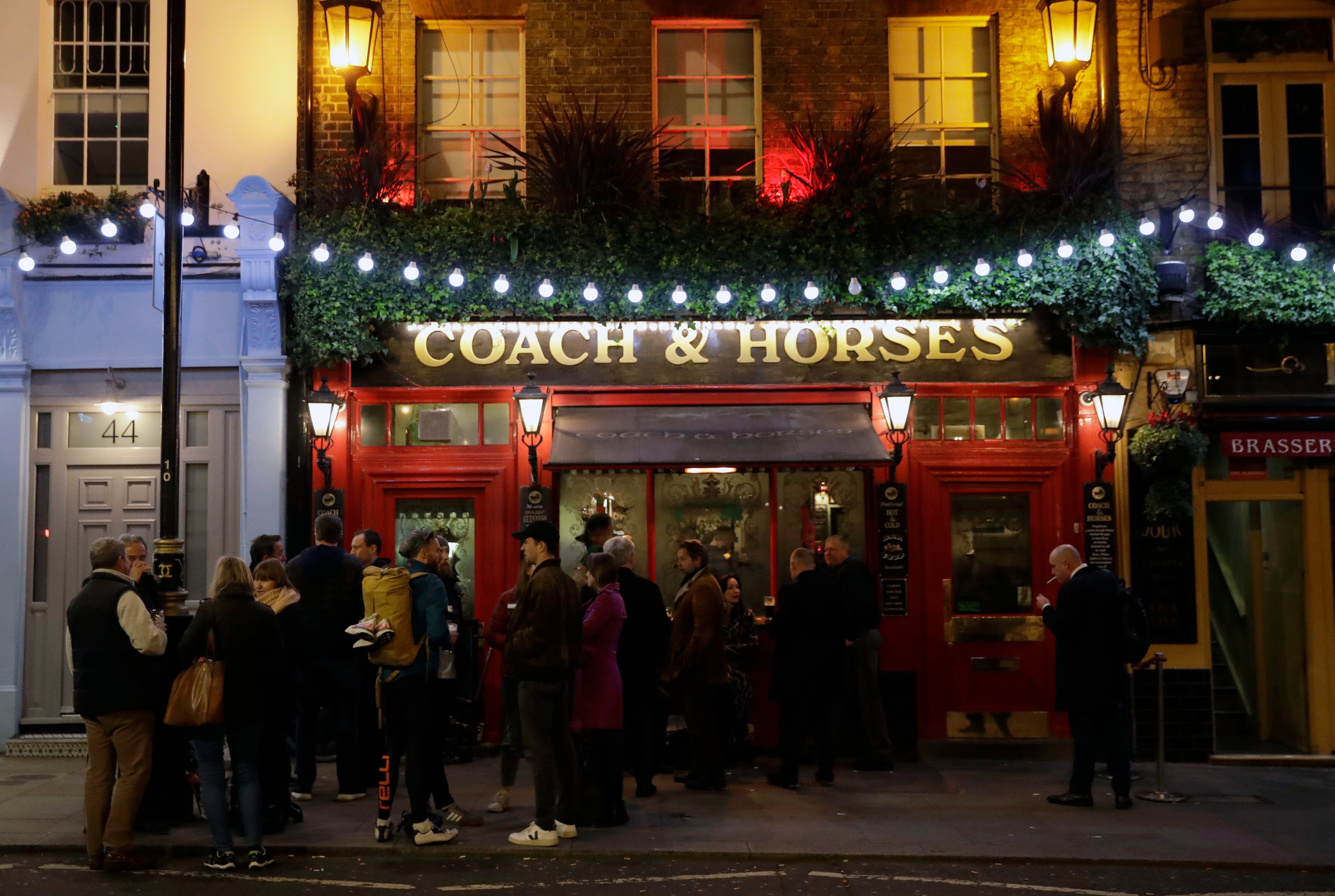 People stand outside the Coach & Horses pub, London, March 17, 2020.