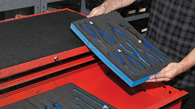 Mechanic organizing blue-handled tools in red Snap-on toolbox with foam inserts