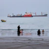 People spend time at a beach as commercial vessels are anchored in the Strait of Hormuz off Bandar Abbas, Iran, Aug. 5, 2026.