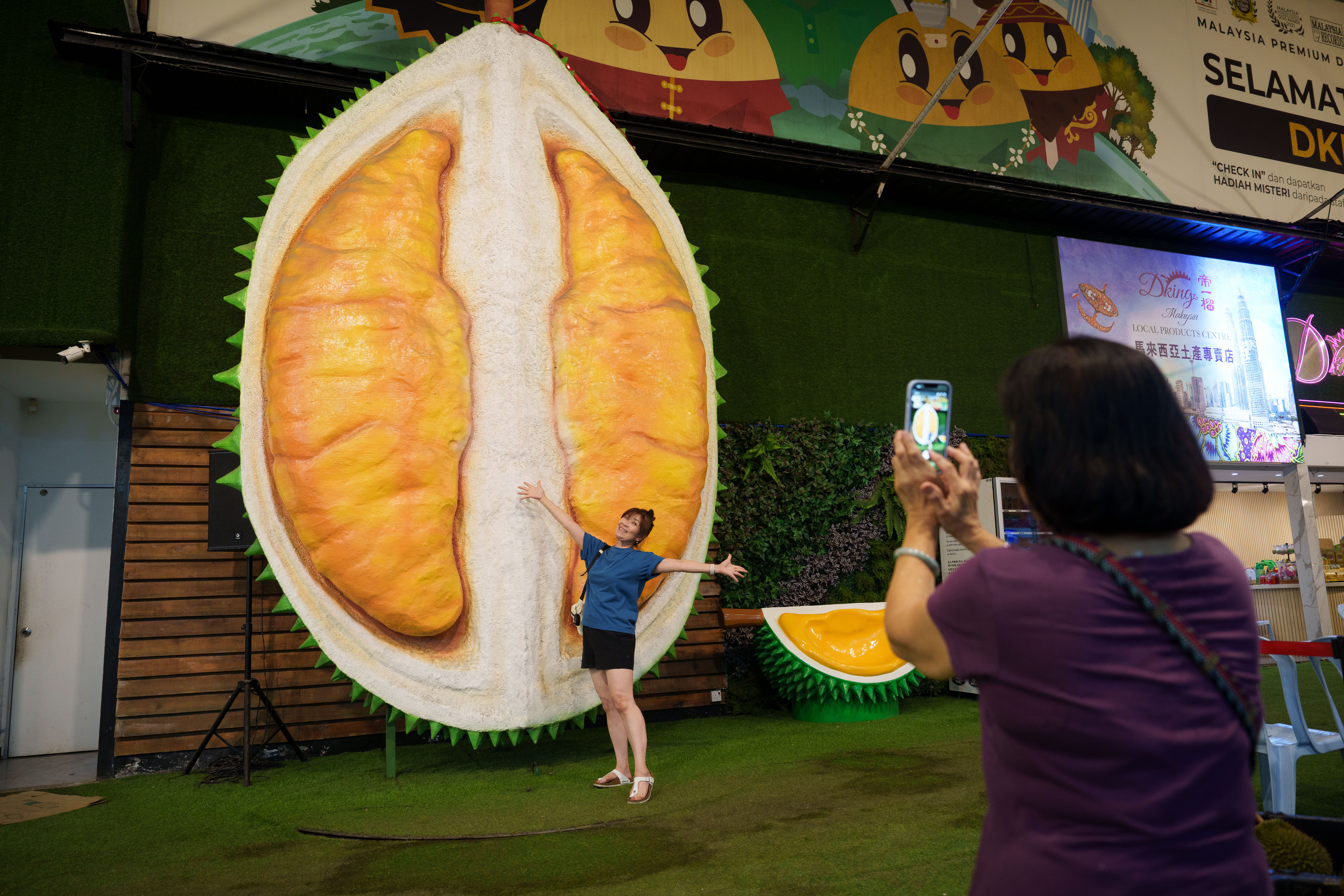 A customer poses beside a giant durian display, Petaling Jaya, Malaysia, June 22, 2026.
