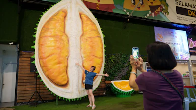 A customer poses beside a giant durian display, Petaling Jaya, Malaysia, June 22, 2026.