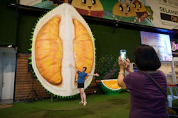 A customer poses beside a giant durian display, Petaling Jaya, Malaysia, June 22, 2026.
