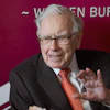 Elderly man in business suit and red tie speaking at event with burgundy background