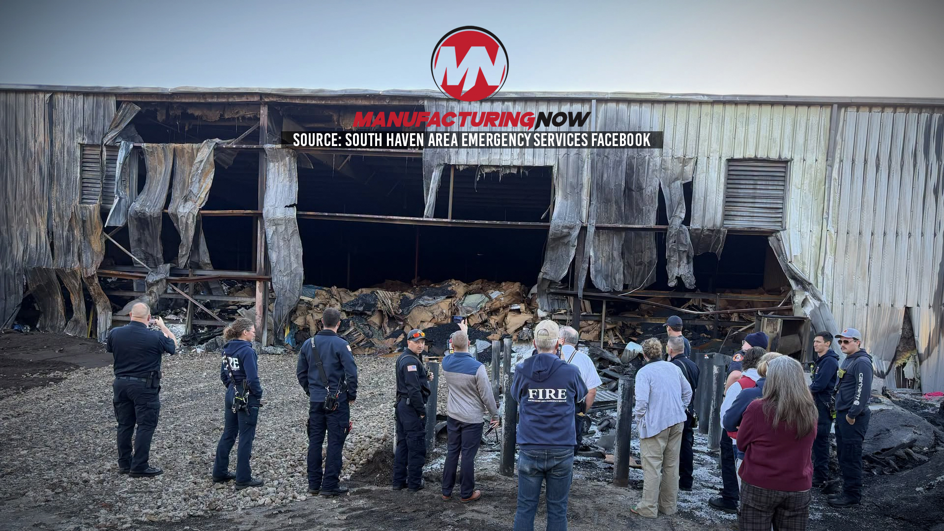 Emergency responders and firefighters assess damage at industrial warehouse with collapsed roof and debris