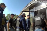 This image from Homeland Security Investigations body camera video shows federal authorities entering the Nutrition Bar Confectioners plant in Cato, N.Y., Sept. 4, 2025.
