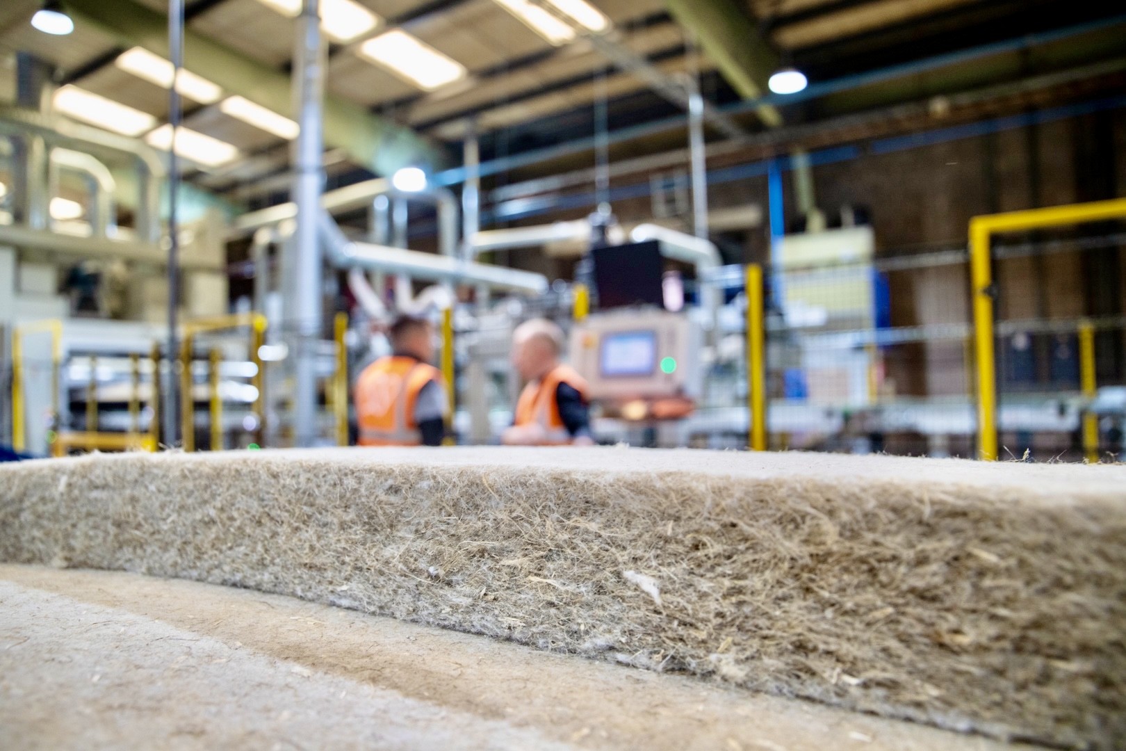 Close-up of concrete material in industrial factory with workers and machinery in background