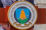 USDA Department of Agriculture seal mounted on wooden plaque featuring wheat sheaf emblem