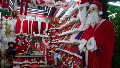A vendor waits for customers near Santa costumes for sale at the Yiwu International Trade Market in Yiwu, eastern China's Zhejiang province on April 10, 2025.