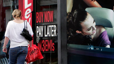 A woman walks by a 'Buy now pay later' sign at a store in Bangalore, India, Sept. 10, 2009.