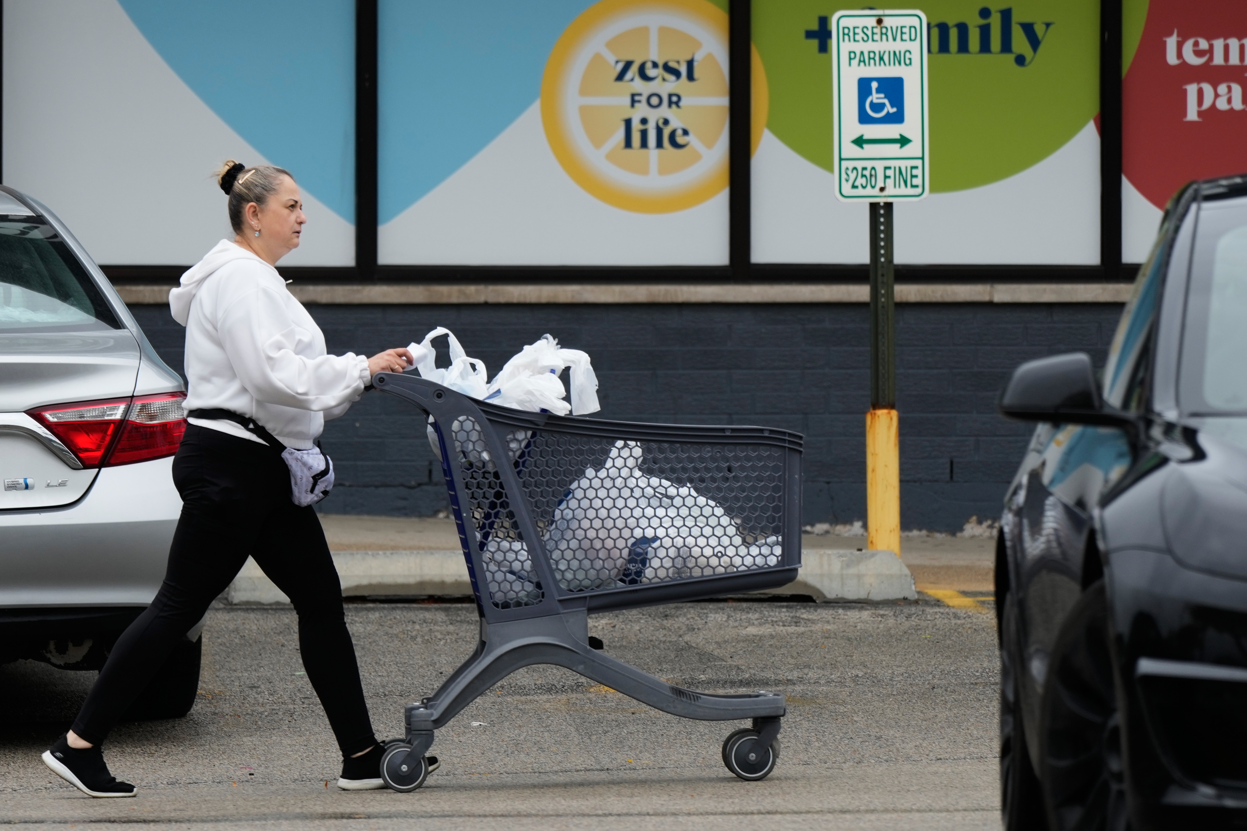 A woman pushes a shopping cart as she leaves a grocery store in Arlington Heights, Ill., Sept. 30, 2026.