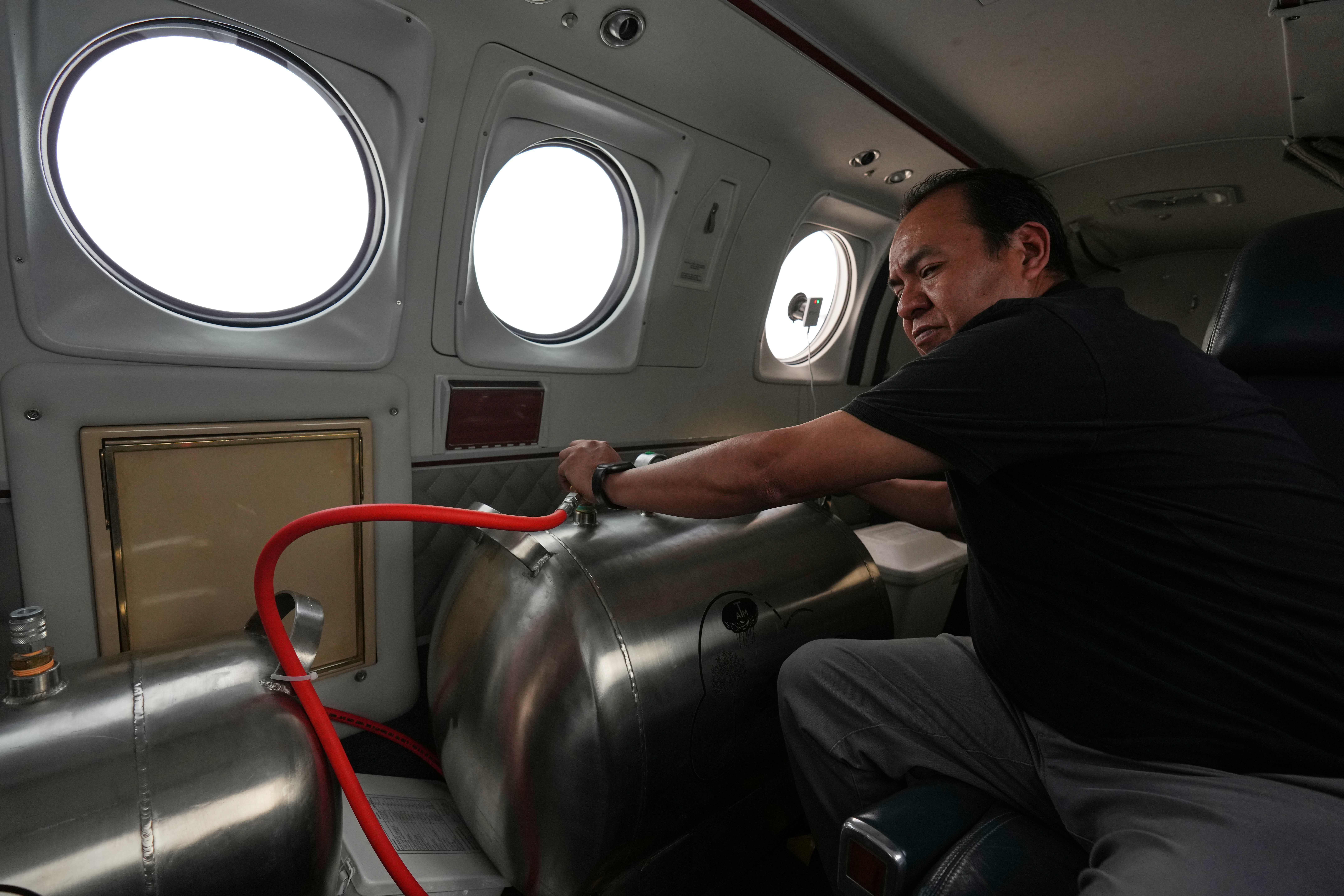 Technician Juan Carlos Diaz operates equipment aboard an aircraft during a cloud-seeding mission, Valle Siria, Honduras, Oct. 14, 2026.