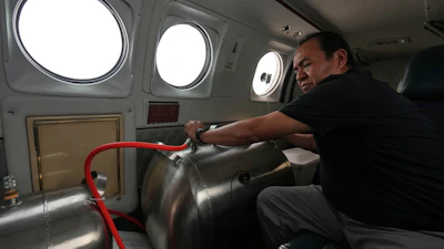 Technician Juan Carlos Diaz operates equipment aboard an aircraft during a cloud-seeding mission, Valle Siria, Honduras, Oct. 14, 2026.