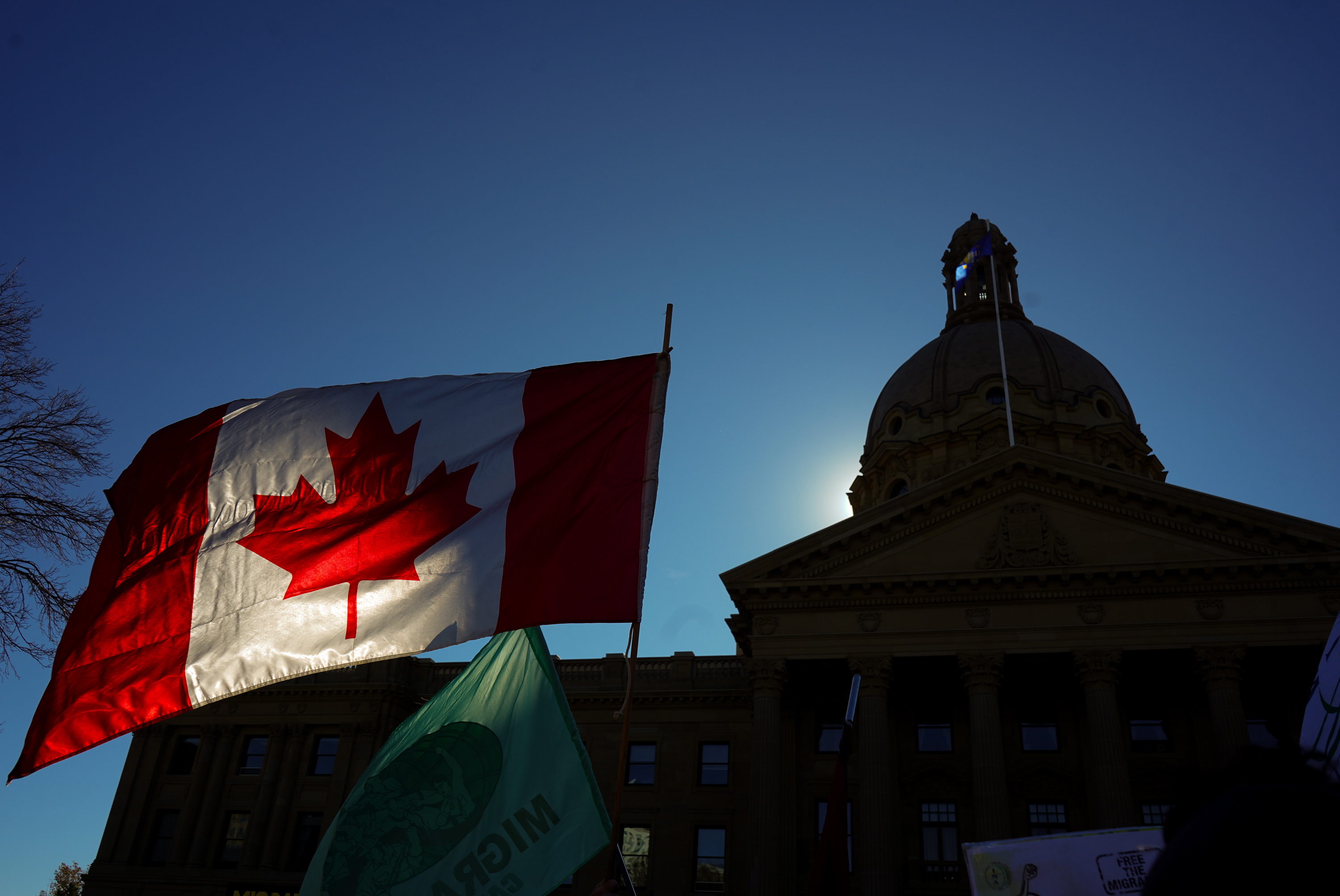 A Canadian flag flies in front of the of the Alberta Legislature during a rally in Edmonton, Oct, 18, 2026.
