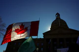 A Canadian flag flies in front of the of the Alberta Legislature during a rally in Edmonton, Oct, 18, 2026.