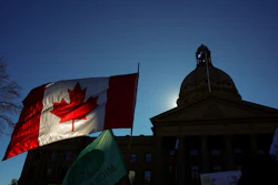 A Canadian flag flies in front of the of the Alberta Legislature during a rally in Edmonton, Oct, 18, 2026.