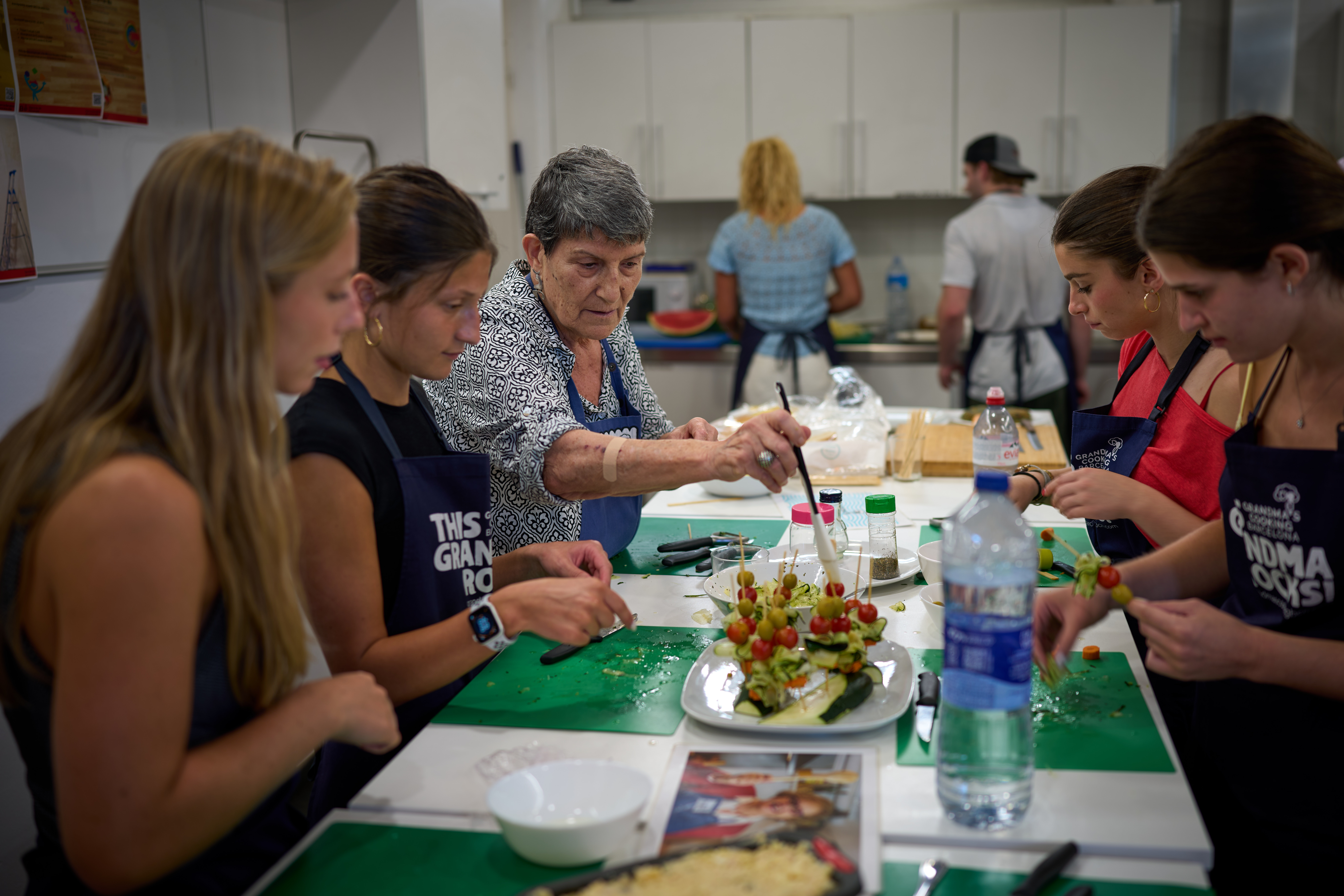 Nuria Isanda, 75, third from left, teaches tourists how to prepare and present traditional Spanish dishes during a cooking workshop at Grandmas Cooking in Barcelona, Oct. 14, 2026.
