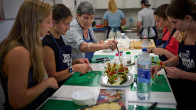 Nuria Isanda, 75, third from left, teaches tourists how to prepare and present traditional Spanish dishes during a cooking workshop at Grandmas Cooking in Barcelona, Oct. 14, 2026.