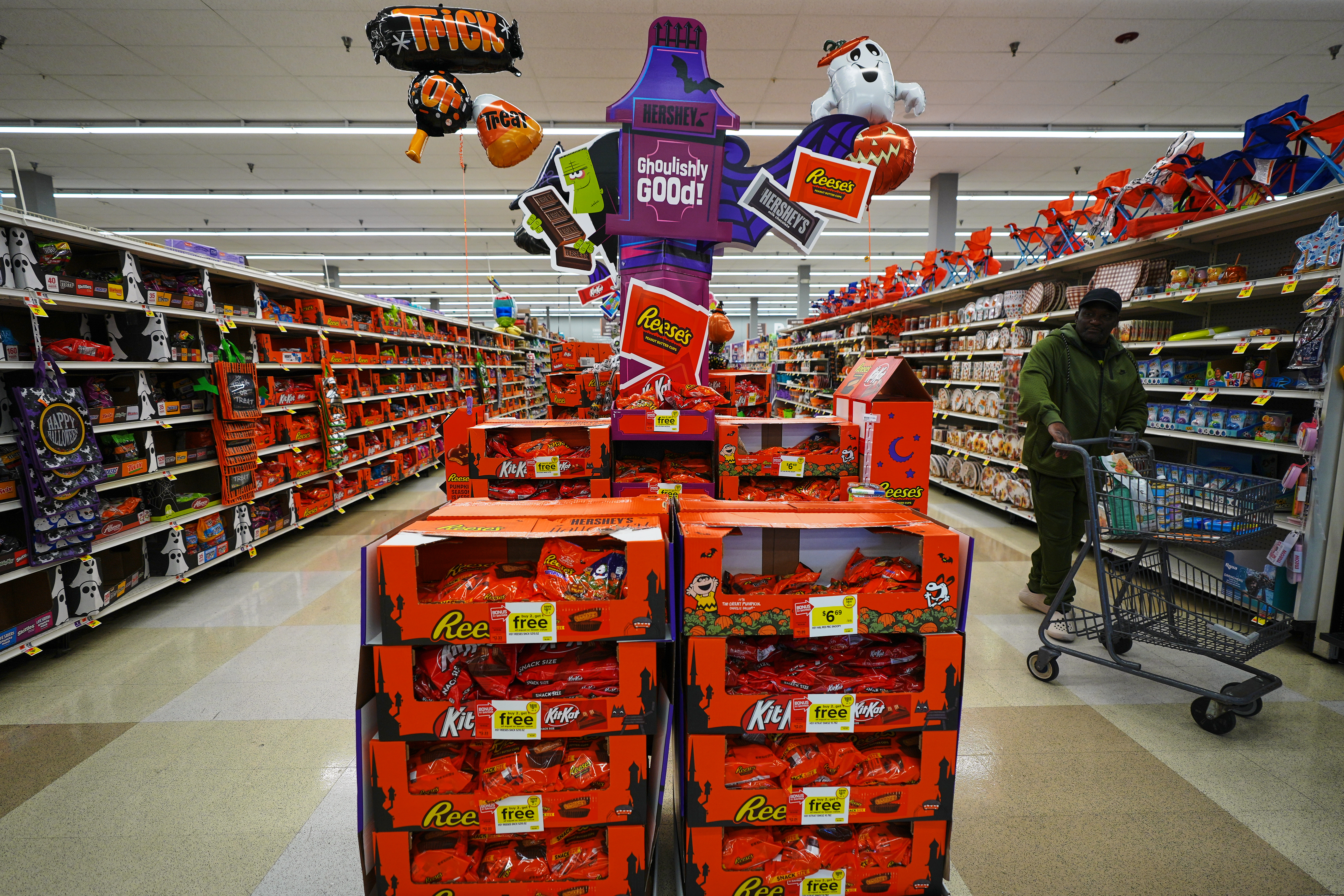 Halloween candy display in retail store featuring Reese's, Kit Kat, and Hershey's products with orange and purple promotional signage.