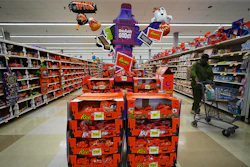 Halloween candy display in retail store featuring Reese's, Kit Kat, and Hershey's products with orange and purple promotional signage.