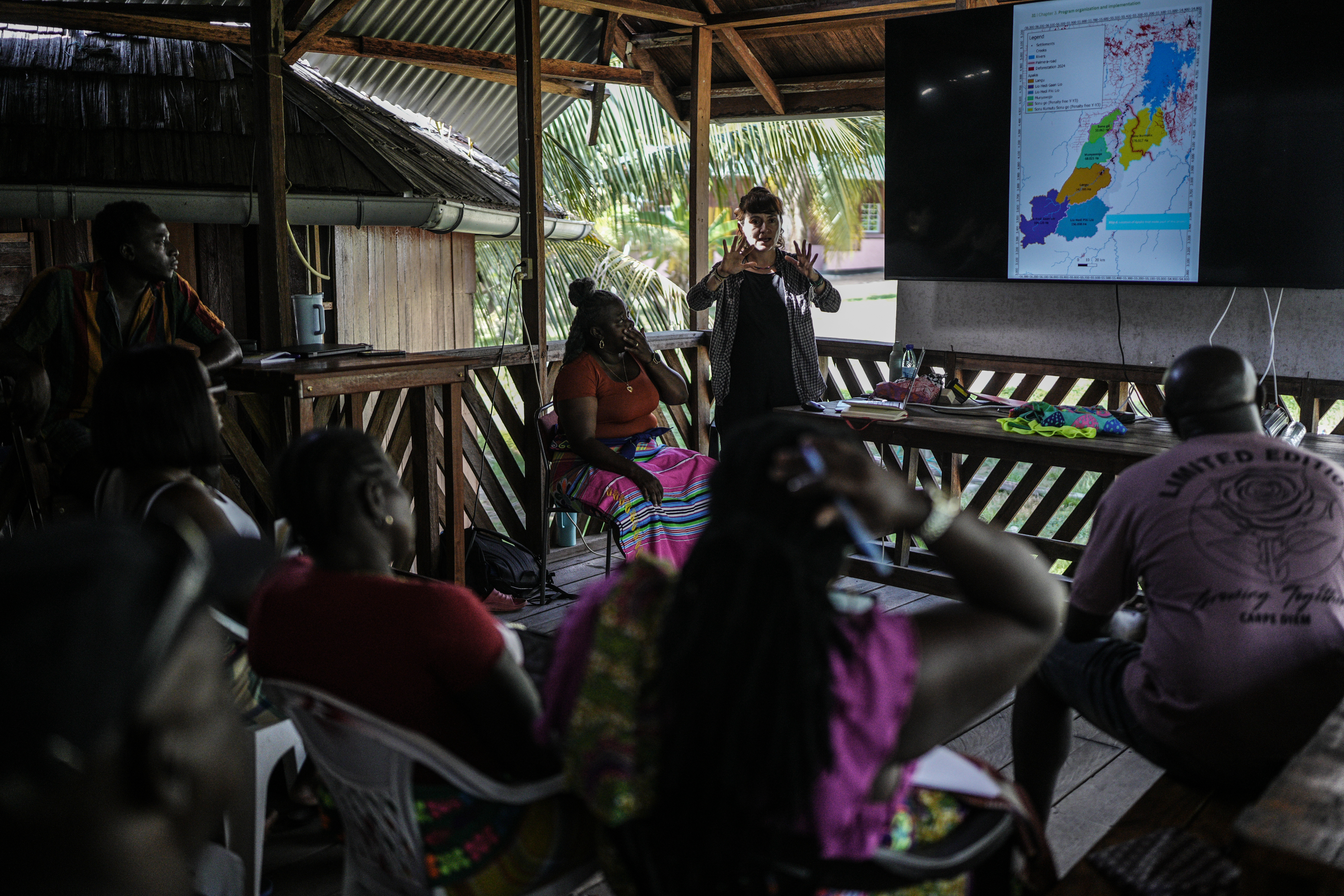 Sara Ramirez, a researcher working for the Association of Saamaka Communities, talks with a group about satellite analysis in Nieuw Aurora, Suriname, Sept. 29, 2026.