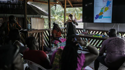 Sara Ramirez, a researcher working for the Association of Saamaka Communities, talks with a group about satellite analysis in Nieuw Aurora, Suriname, Sept. 29, 2026.