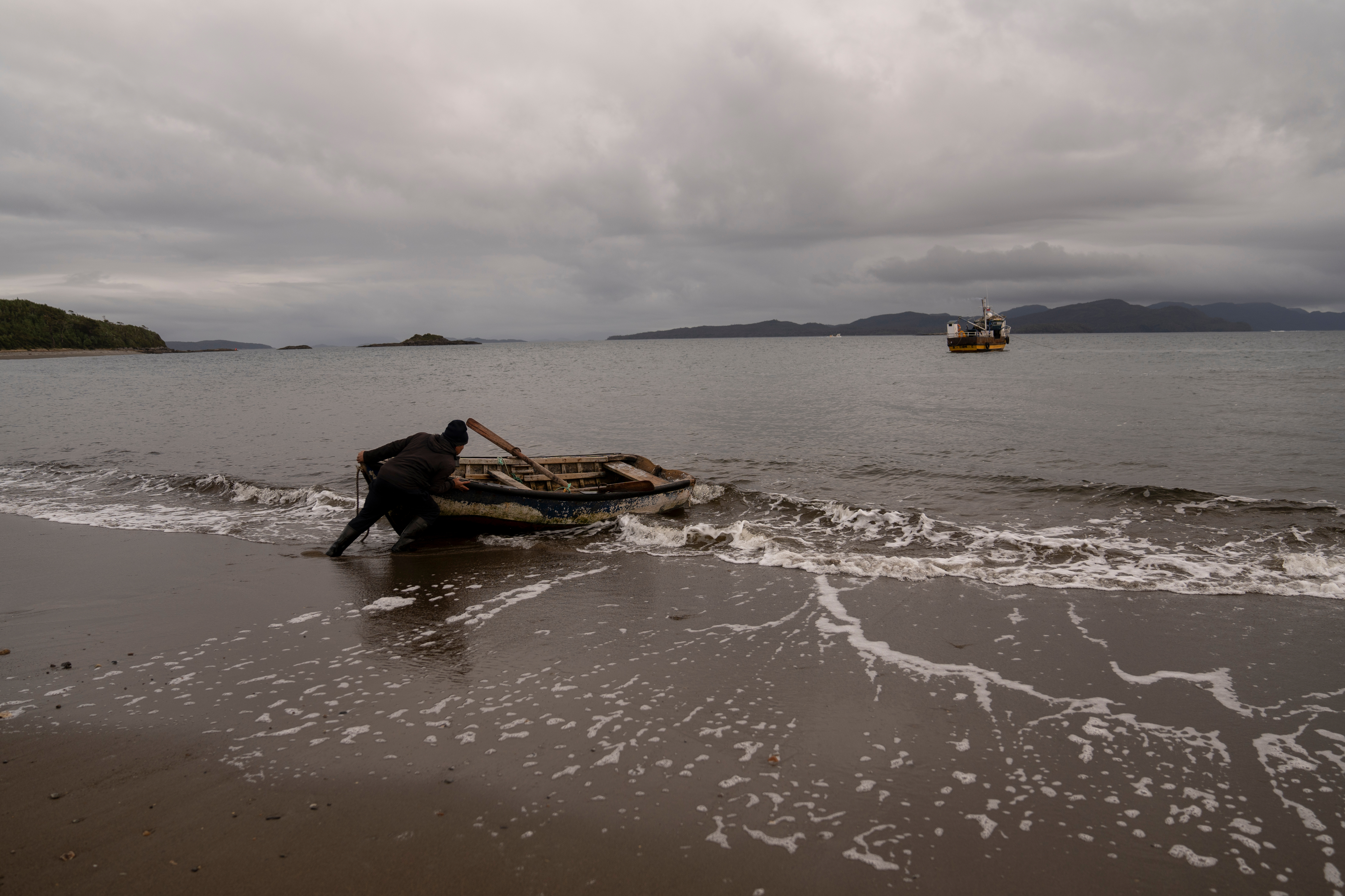 Daniel Arturo Caniullan Huentel, leader of the Indigenous Mapuche Pu Wapi community and a shellfish fisher, pushes a boat into the water before rowing out to his fishing boat in the Guaitecas Archipelago, Chile, May 22, 2025.