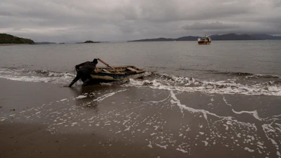 Daniel Arturo Caniullan Huentel, leader of the Indigenous Mapuche Pu Wapi community and a shellfish fisher, pushes a boat into the water before rowing out to his fishing boat in the Guaitecas Archipelago, Chile, May 22, 2025.