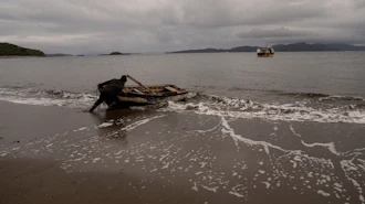 Daniel Arturo Caniullan Huentel, leader of the Indigenous Mapuche Pu Wapi community and a shellfish fisher, pushes a boat into the water before rowing out to his fishing boat in the Guaitecas Archipelago, Chile, May 22, 2025.