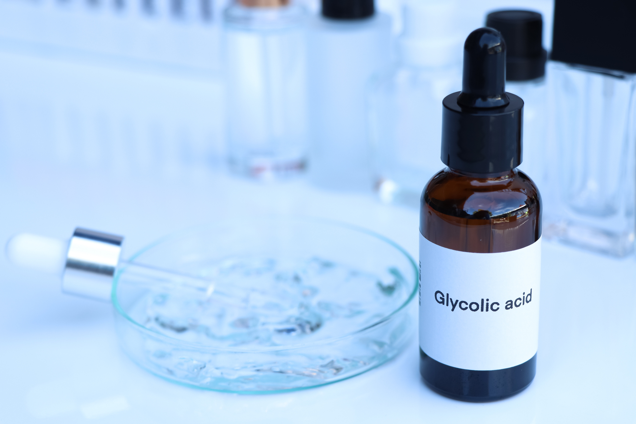 Glycolic acid bottle with dropper in laboratory setting with petri dish and test tubes