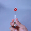 Hand holding a medical diagnostic test device with red collection sphere against blue background