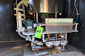 Industrial machinery with motor and metal components inside black cabinet with green asset tag