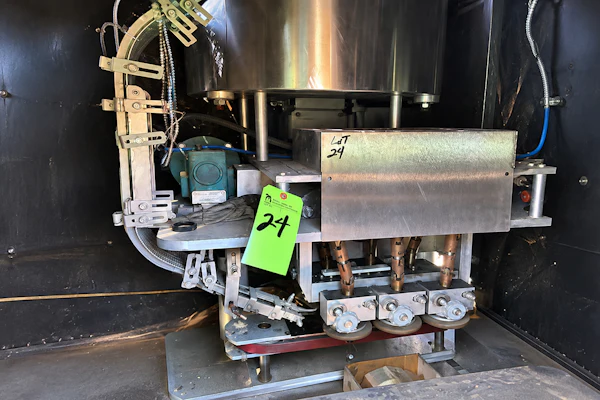 Industrial machinery with motor and metal components inside black cabinet with green asset tag